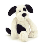 The Jellycat Bashful Black & Cream Puppy plush has black ears, a patch over one eye, and a side spot, all on a white base.