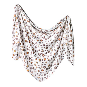 The Knit Swaddle Blanket, Millie by Copper Pearl features a loose polyester-rayon leopard print on white, ideal for stylish swaddling.