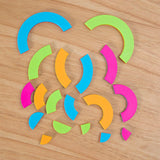 The Bugzzle Game by Fat Brain Toy Co uses colorful geometric shapes in green, blue, pink, and orange for a math challenge on wood.