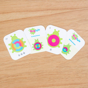 Bugzzle Game by Fat Brain Toy Co features four colorful, circular-patterned cards titled Buggzle and Solution for a brain challenge.