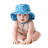 A baby wears Bumkins Sun Hat: Ahoy, a blue, nautical print hat with adjustable drawstring and UPF 50+ protection on a white background.