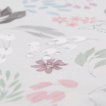 Close-up of water droplets on Bumkins SuperBib®s waterproof, floral fabric with pink, green, and gray leaves.