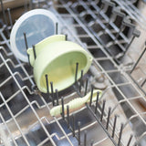 The Bumkins Silicone First Feeding Set in Sage, with a suction bowl, lid, and spoon, can be placed on the top rack of the dishwasher.