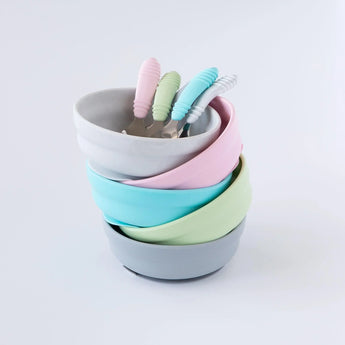 Five bowls and spoons, including Bumkins Silicone Grip Bowl: Gray, sit stacked on a white background.