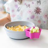 Bumkins Silicone Grip Bowl: Gray with macaroni and cheese, and a pink star-shaped dish of cucumbers sits on a white table.