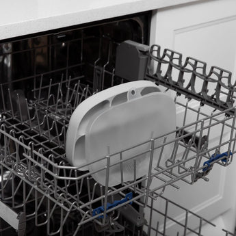 Open dishwasher with Silicone Grip Dish: Gray by Bumkins on the tray, featuring a food-safe silicone design. Kitchen counter in background.