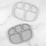 Two gray Bumkins Silicone Grip Dishes with lids (5 sections), made of food-safe silicone, on a white marble surface.