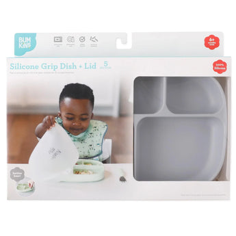 A child enjoys food from a Bumkins Silicone Grip Dish with 5 sections; an empty Gray dish awaits, featuring compartments and a leak-resistant lid.