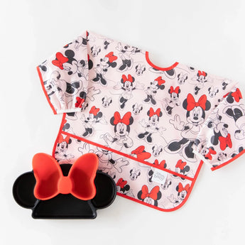 A waterproof sleeved bib and silicone plate from Bumkins Disney Little Ones Gift Bundle: Minnie Mouse Classic lay on a white background.