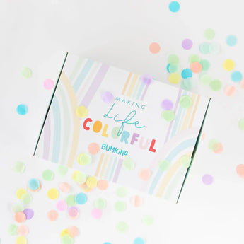 A colorful gift box for Bumkins Ultimate Gift Set - Dinosaurs & Blue Tropic surrounded by confetti on a white background.