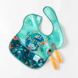 A jungle-themed bib and orange utensils from Bumkins Ultimate Gift Set - Jungle & Animal Prints lay on a white background.