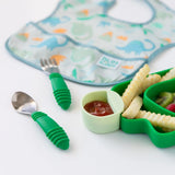 A green Bumkins Silicone Little Dipper Round 3-Pack: Gumdrop filled with ketchup among a plate, utensils and a bib on a white background.