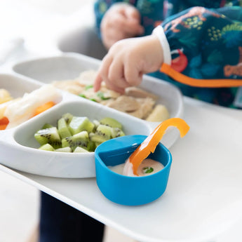 Close-up of a blue Bumkins Silicone Little Dipper Round 3-Pack: Gumdrop with dip and a bell pepper slice attached to a gray plate of food.
