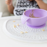 Close-up of a purple bowl sitting on a Bumkins Silicone Sensory Placemat: Marble on a white table.