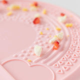 Close-up of bits of food scattered on a Bumkins Silicone Sensory Placemat: Pink.