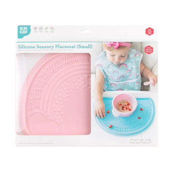 Bumkins Silicone Sensory Placemat: Pink is shown in a packaging box with a photo of a child and a front window partially showing the placemat.