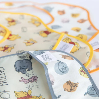 Close-up of Bumkins SuperBib® 3 Pack: Pooh Bear and Friends on a white background, with focus on the front pocket.