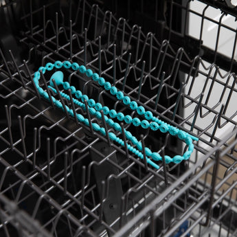 Bumkins Silicone Accessory Tether 2-Pack: Blue sits in the top rack of an open dishwasher.