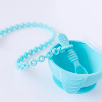 A blue bowl with a spoon attached to a Bumkins Silicone Accessory Tether 2-Pack: Blue on a white background.
