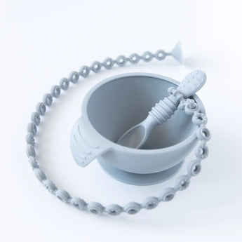 A gray bowl with a gray spoon attached to a Bumkins Silicone Accessory Tether 2-Pack: Gray on a white background.