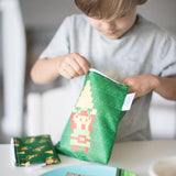 A child opens a green Bumkins lunch bag featuring The Legend of Zelda™, next to similar reusable sandwich bags.