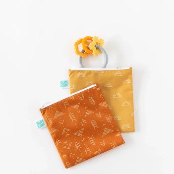 Bumkins Reusable Snack Bag, Large 2-Pack: Sunshine and Grounded lays overlapped on a white background, with an orange teething toy nearby.