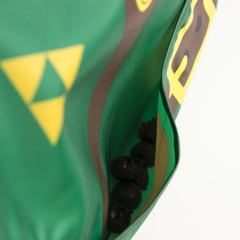Close-up of Bumkins Caped SuperBib®: The Legend of Zelda™ Link, green with brown and yellow design, showing black spheres inside.