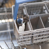 Open dishwasher with cutlery in a utensil basket, featuring Bumkins Spoon + Fork: Gray toddler set.