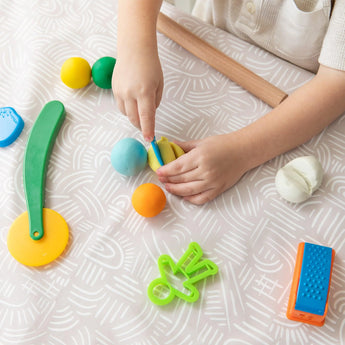 A child plays with colorful clay on a Bumkins Splat Mat: Wander.