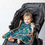 A baby in a stroller wears a Bumkins Super-Sized SuperBib®: Jungle, holding a snack pouch.