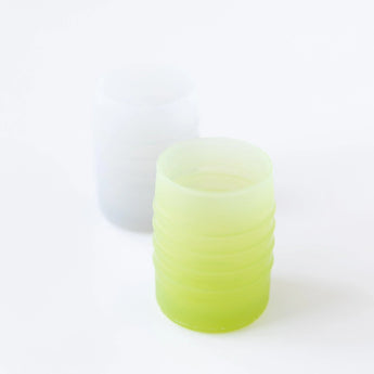 Bumkins Silicone Starter Cup: Sage sits on a white background, with a gray cup blurred in the background.