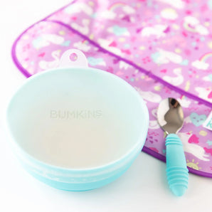 Bumkins Silicone Stretch Lid for Grip Bowl covers a blue bowl next to a blue spoon and purple bib on a white background.