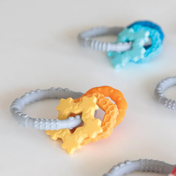 Bumkins Silicone Teething Charms: Orange lays among other teething toys on a white background.