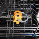 Bumkins Silicone Teething Charms: Orange sits in the top rack of an open dishwasher.