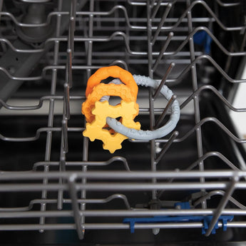 Bumkins Silicone Teething Charms: Orange sits in the top rack of an open dishwasher.