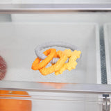 Close-up of Bumkins Silicone Teething Charms: Orange inside a refrigerator.