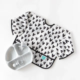 Bumkins Sleeved Bib: Hearts with crumb catcher next to a marbled gray divided plate and utensils on a white background.