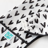 Close-up of a Bumkins Sleeved Bib: Hearts, showcasing black and white heart patterns on a waterproof fabric.
