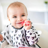 Happy baby in a Bumkins Sleeved Bib: Hearts, holding a pink toy while seated in a high chair. Waterproof and adorable!.