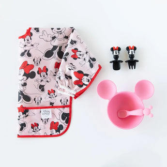 The Bumkins Sleeved Bib: Minnie Mouse set includes a waterproof bib, pink bowl, spoon, and bib clips on a white backdrop.