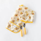 Bumkins Sleeved Bib: Winnie Loves Hunny lays folded on a white background with a yellow fork and spoon.