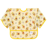 Bumkins Sleeved Bib: Winnie Loves Hunny features yellow waterproof fabric with playful Winnie the Pooh illustrations and a front pocket.