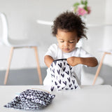 Toddler opens a Bumkins Reusable Snack Bag in Hearts design at a table, next to another bag from the Large 2-Pack: XOXO & Hearts.