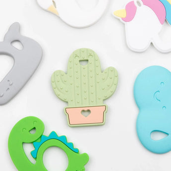 Bumkins colorful silicone teethers feature shapes like cactus, whale, & unicorn on a white base for baby teething relief.