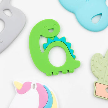 Bumkins Silicone Teether: Dinosaur with a smile, perfect for soothing baby gums, paired with colorful unicorn and cactus toys.