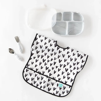 Bumkins Junior Bib: Hearts, stain-resistant, with gray plate and white utensils on a white background.