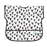 The Junior Bib: Hearts by Bumkins is white with black hearts, a pocket, and logo. Made of waterproof, stain-resistant fabric.