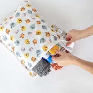 Hands organize items in a bag from Bumkins The Chaos Coordinator Deluxe 5-Piece Set: Disney Pooh Bear + Friends on a white background.