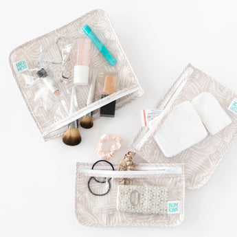 Bumkins Clear Travel Bag 3-Pack: Wander holds makeup, brushes, scrunchies, and toiletries on a white background.
