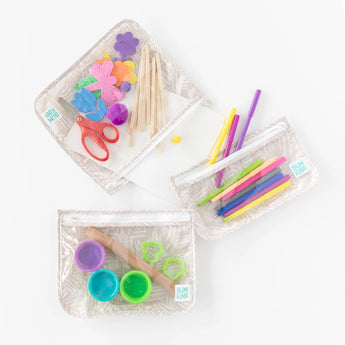 Bumkins Clear Travel Bag 3-Pack: Wander holds foam flowers, popsicle sticks, scissors, pens, clay, and cookie cutters on a white background.